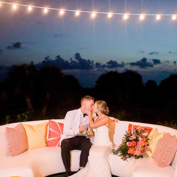Newlyweds kissing on white curved sofa rental from Niche Event Rentals | Maria Glassford Photography